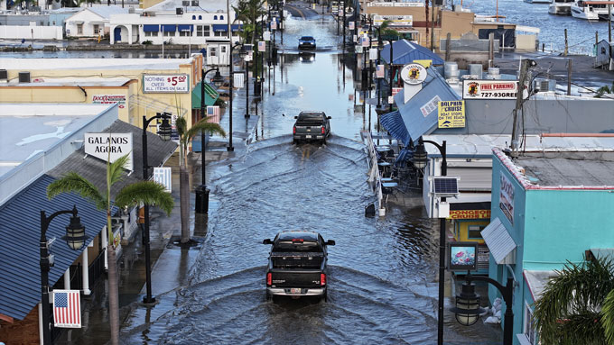 Trucks drive through a flooded street.